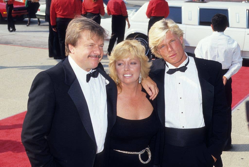 Betty stands between her husband John Karlen and son Adam in a black dress with a belt and silver earrings.