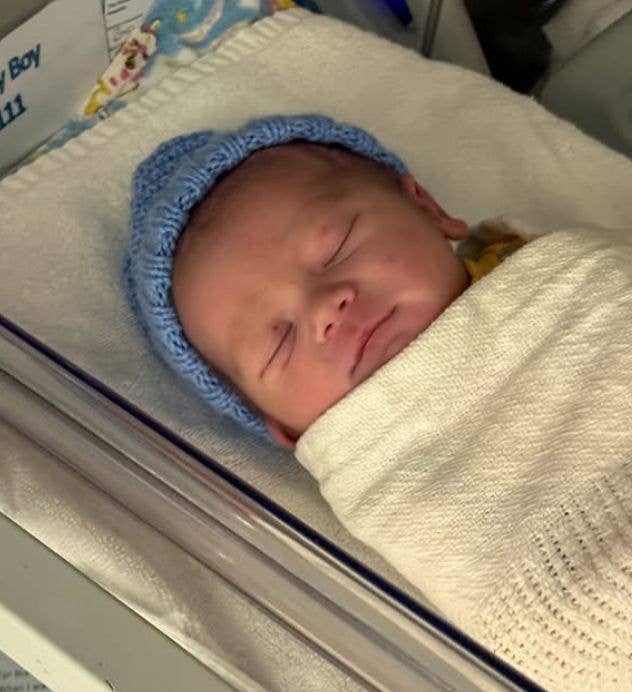 A baby sleeping in a blue knit hat and blanket