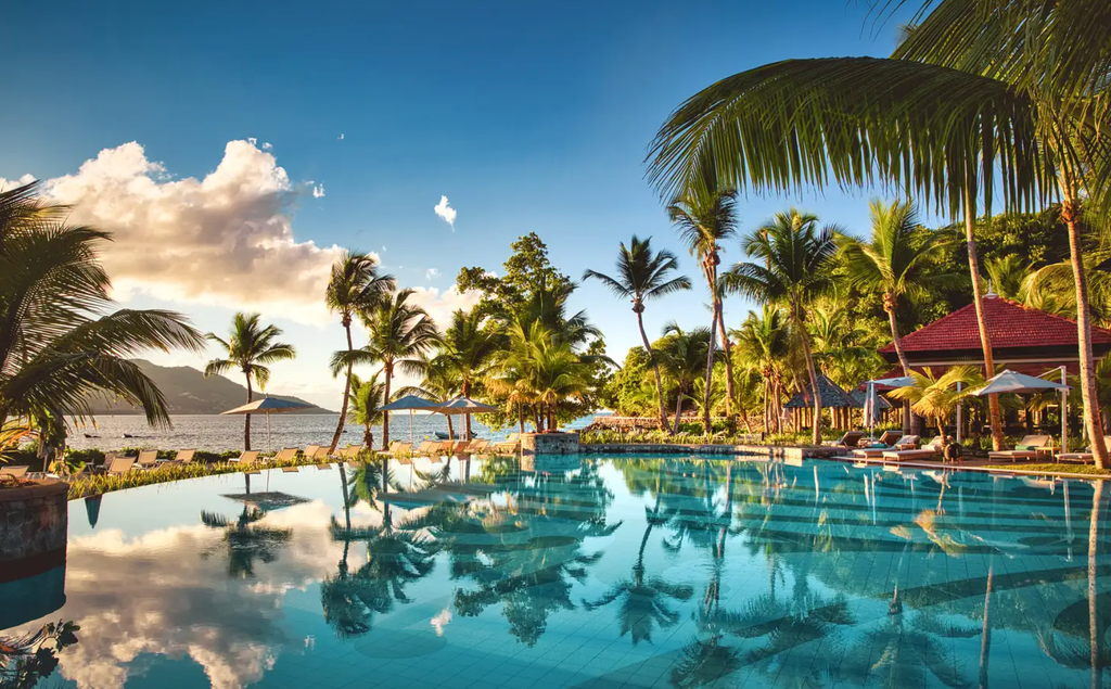 Pool looking over a beach with sun setting 