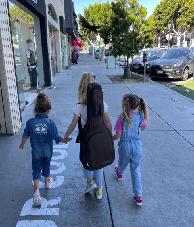 Three young girls walking down a street hand-in-hand