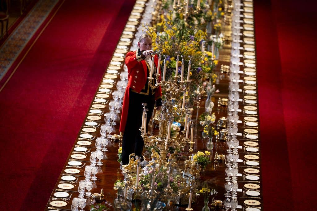 A member of Royal Household staff lights a candle during table preparations in St George's Hall, ahead of the state banquet for Nigerian President Bola Ahmed Tinubu and First Lady Oluremi Tinubu on day one of their state visit to the UK at Windsor Castle on March 18, 2026 in Berkshire, England. (Photo by Aaron Chown - WPA Pool/Getty Images)