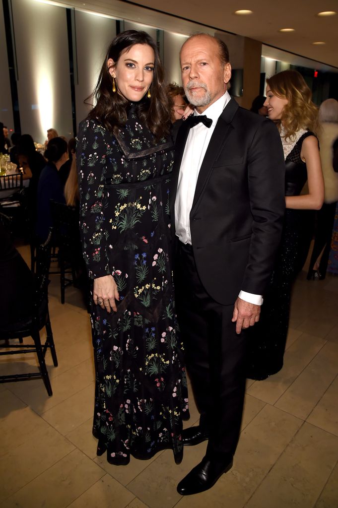 Bruce Willis stands next to Liv Tyler who wears an embellished black, high neck gown.