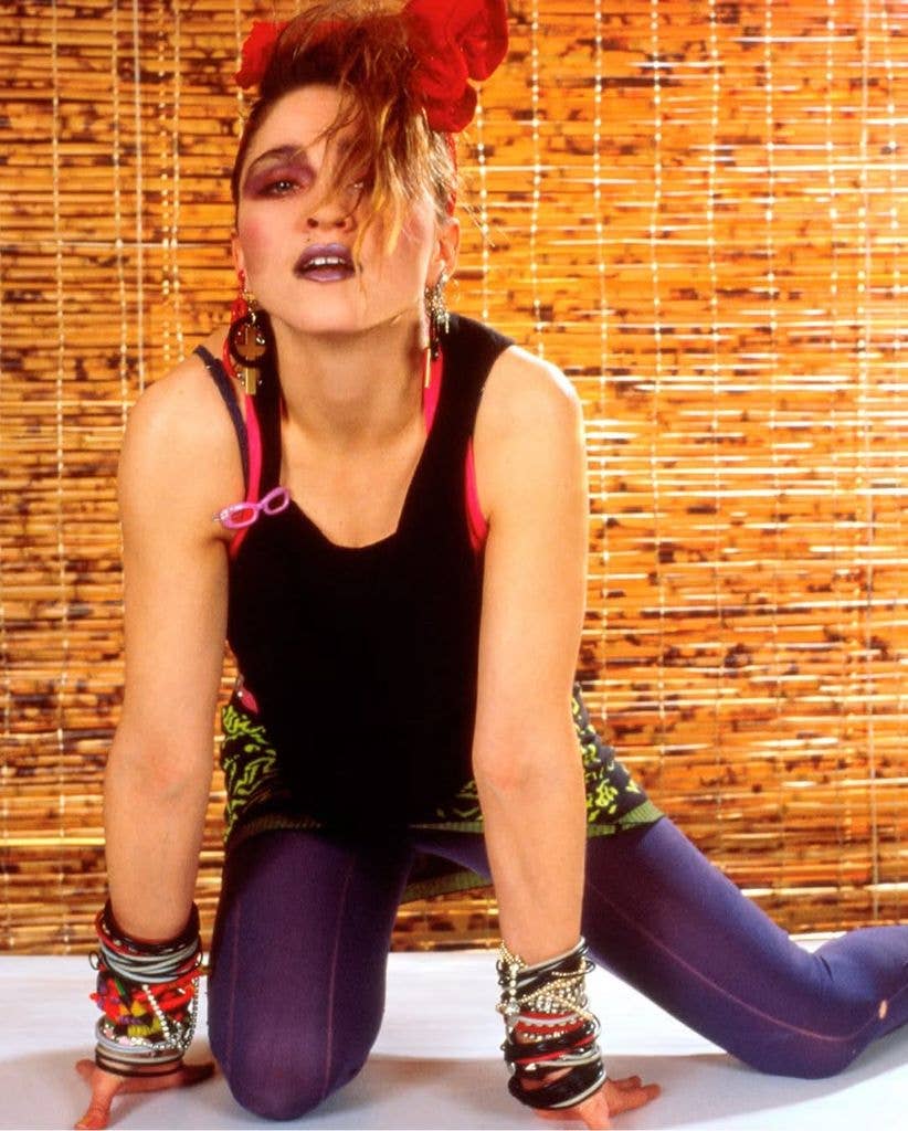 Madonna bold eye make-up, big bows in her hair, jewellery, dressed in purple leggings