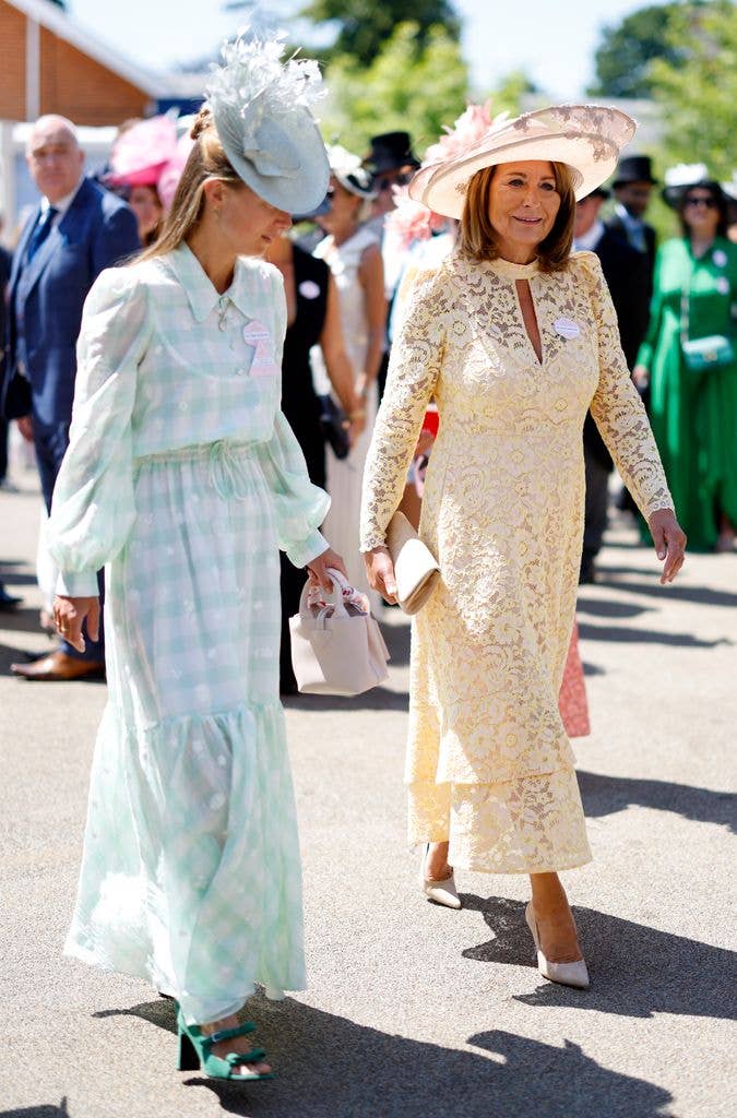 Alizee in green hat and dress walking beside carole middleton in yellow