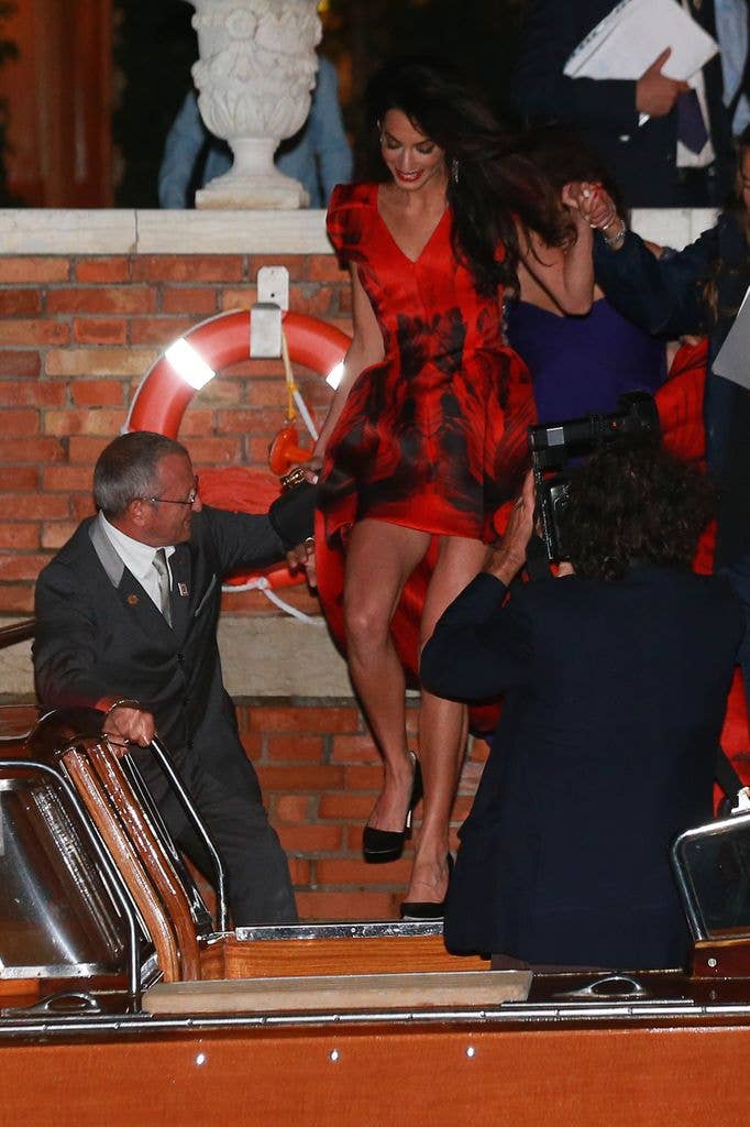 Amal boarding boat in red and black dress  