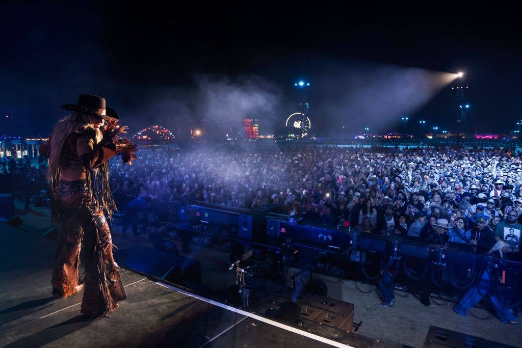 Lainey Wilson performing on stage to thousands