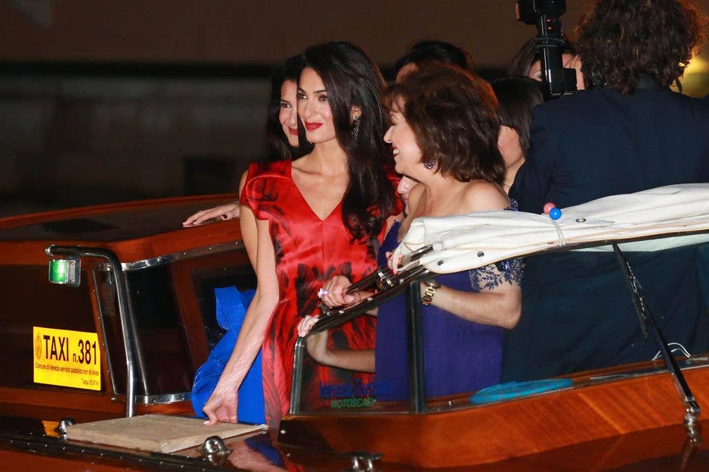 Amal on boat in red dress at night