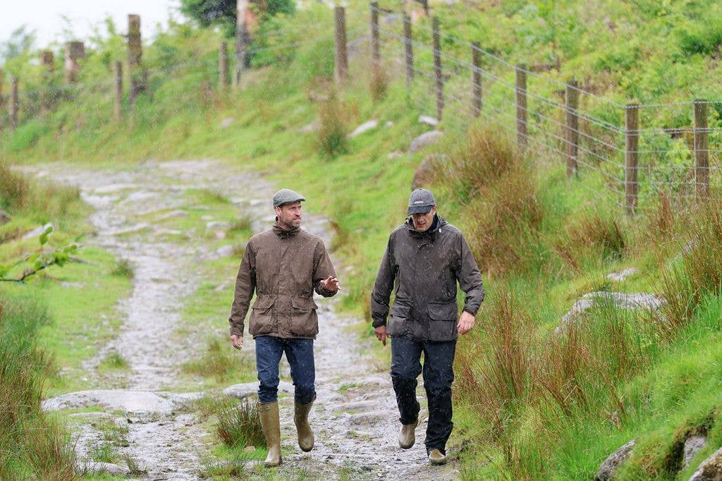 Prince William walking through peatbog with man in wellies