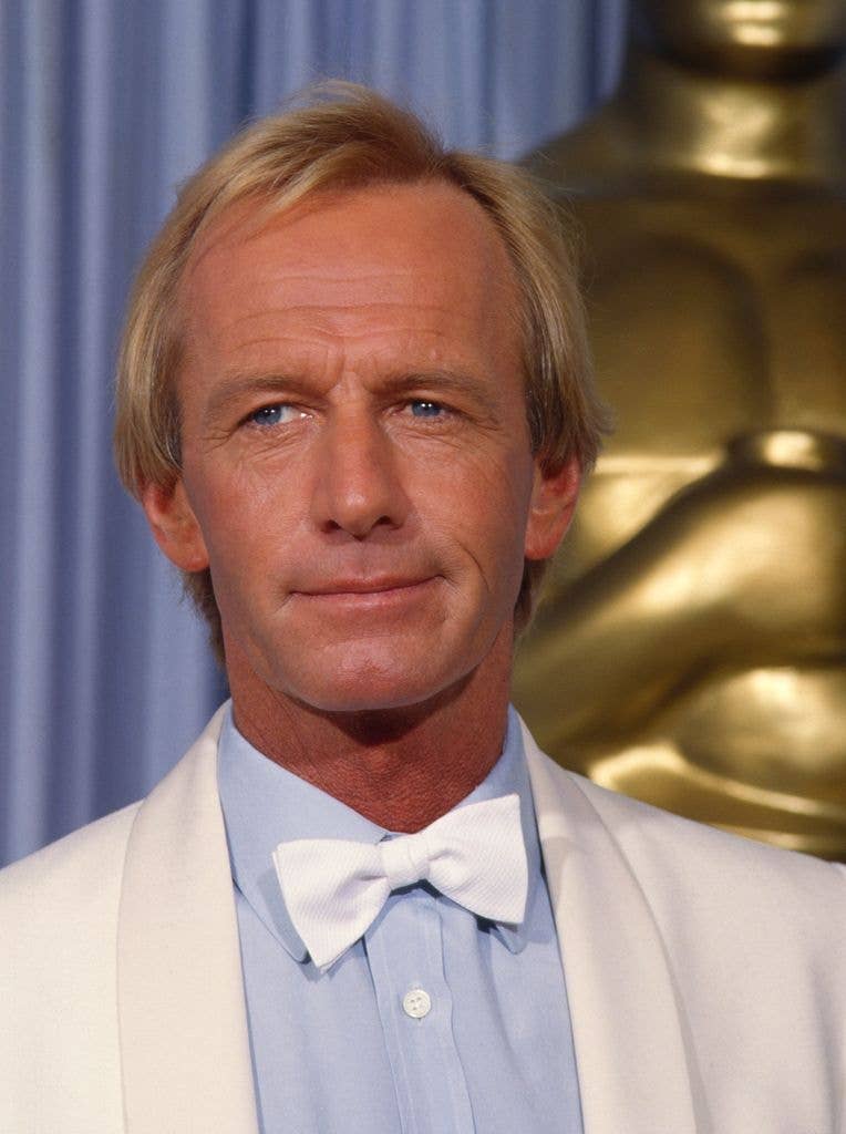 Paul Hogan in a white suit jacket, white bowtie and light blue shirt at the Academy Awards in 1986.
