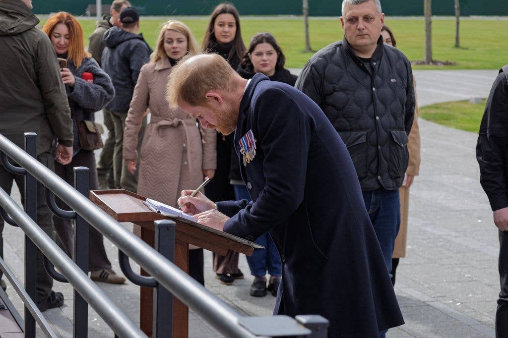 Harry signs the guest book as he visits The National War Memorial Cemetery