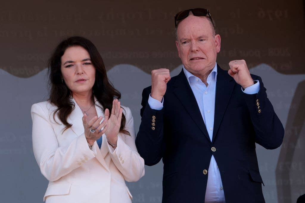 Prince Albert with fists up next to Melanie-Antoinette de Massy in sport stands