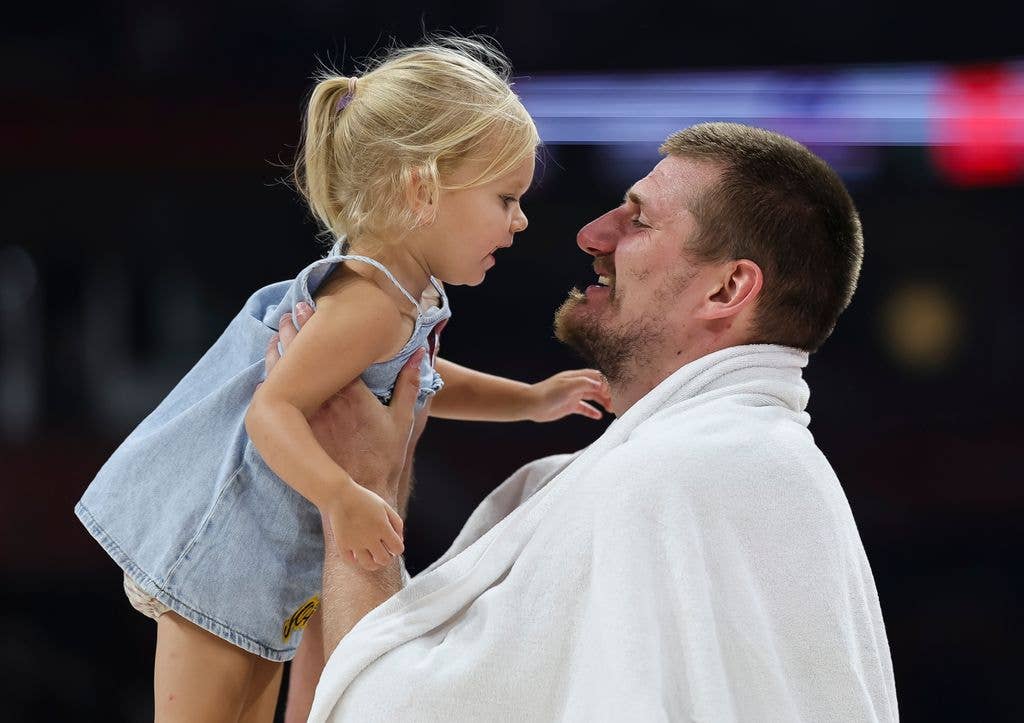 photo of nikola jokic holding daughter in the air