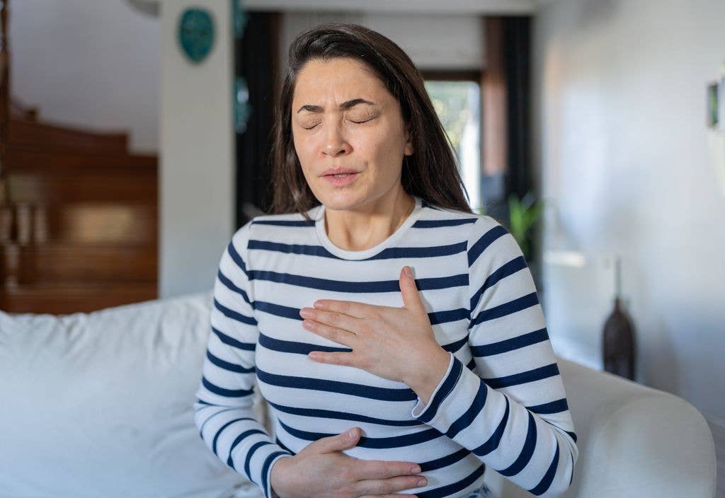 Woman With A Panic Attack Having Trouble Breathing Sitting On Sofa At Home