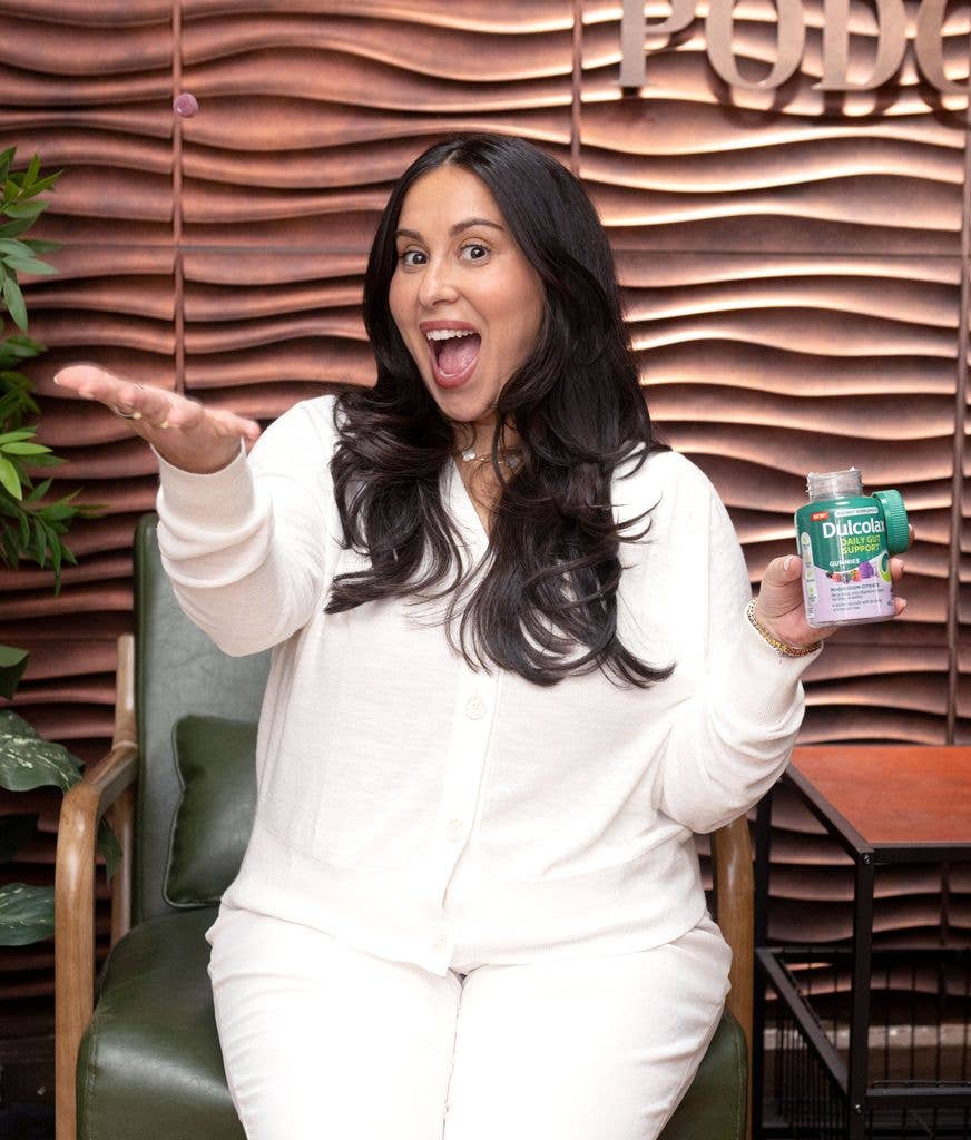Claudia with a bottle wearing all white and smiling 


