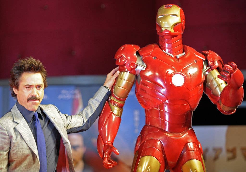 Robert Downey Jr. poses by a life-size Iron Man model 