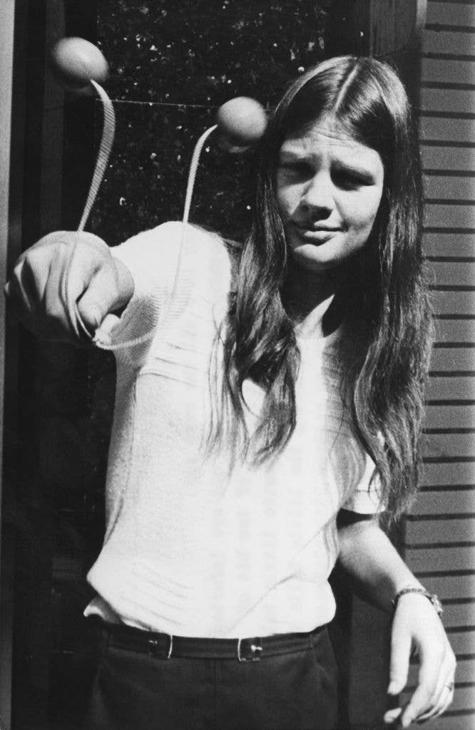 Black-and-white photo of a child playing with clackers