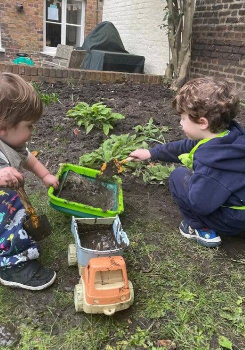 Two young children playing in a garden and getting muddy