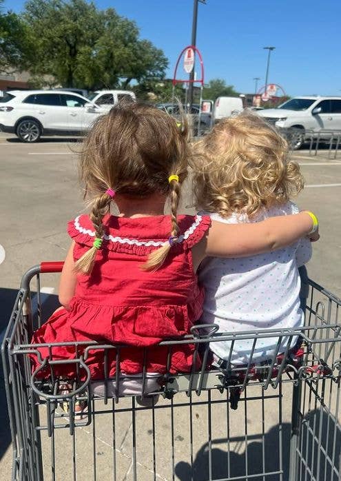 Two children with their arms wrapped around each other riding in a trolley