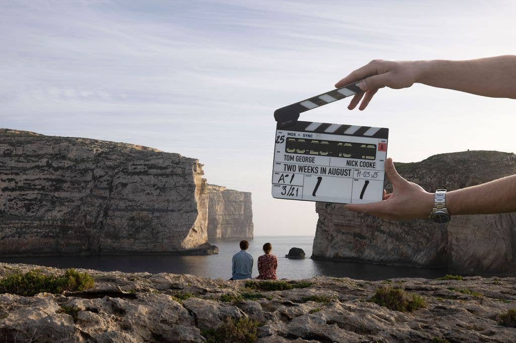 clapper board in front of two people on the beach