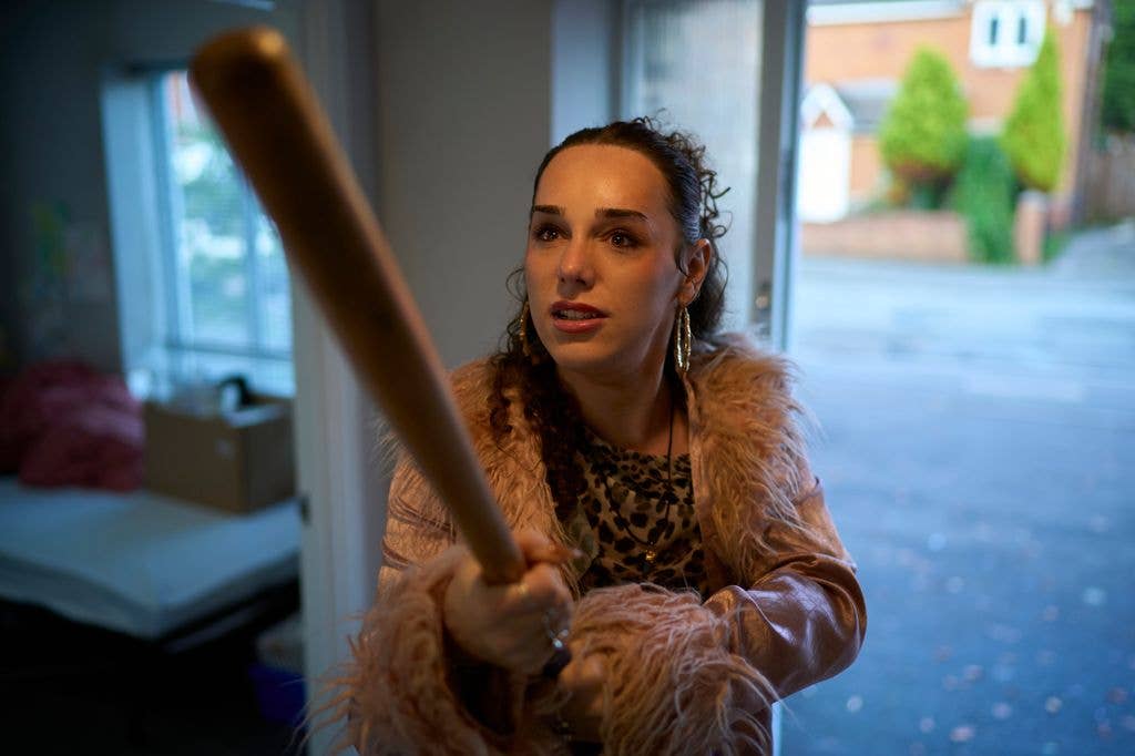 Iz Hesketh holding a baseball bat in a still image from Tip Toe