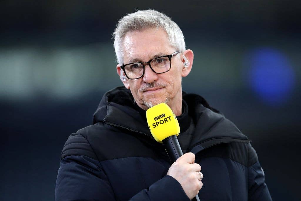 Gary Linekar wearing a black coat and holding a bright yellow BBC Sport microphone.