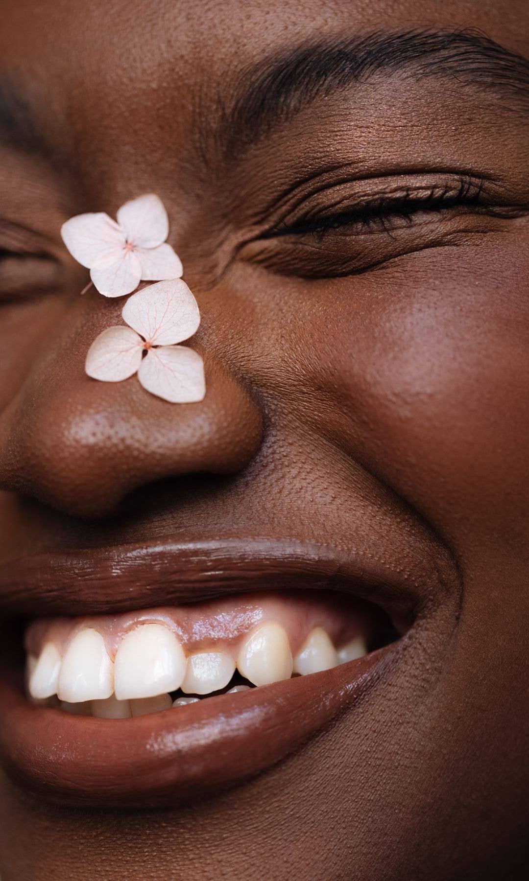 Close up of model smiling with flowers on her nose 