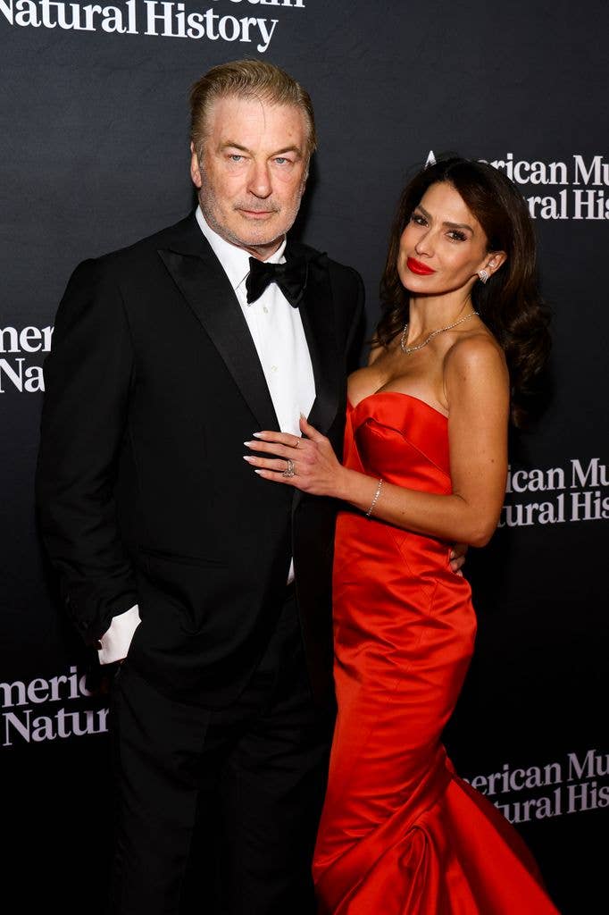 Michael Baldwin wears a traditional suit with a black bowtie and stands next to wife Hilaria who wears a red satin strapless mermaid dress.