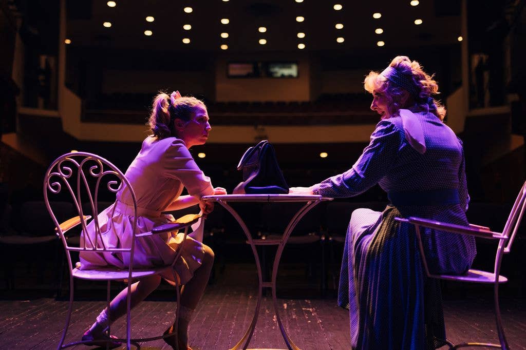 Two actresses on the stage of the theater, rehearsing the performance of the play illuminated by the theater lights