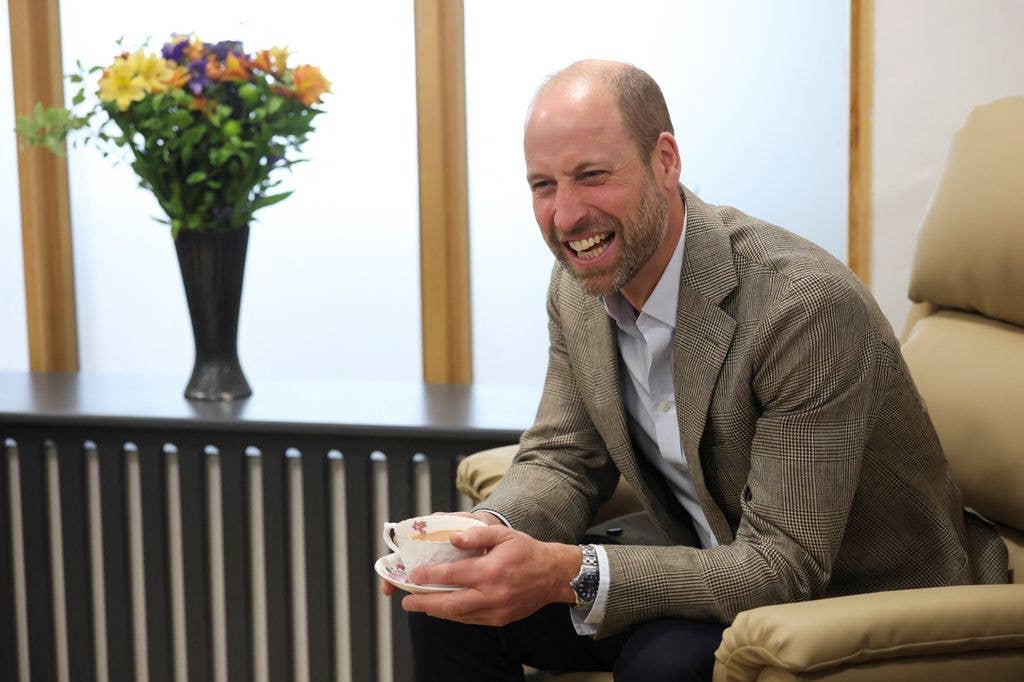 Prince William laughing with a cup of tea during his visit to the Isles of Scilly Hospital
