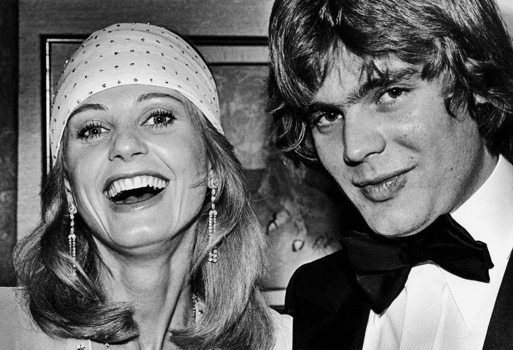 Jill Ireland smiles in a spotted bandana and stands next to son Jason McCallum who wears a tux and bowtie.