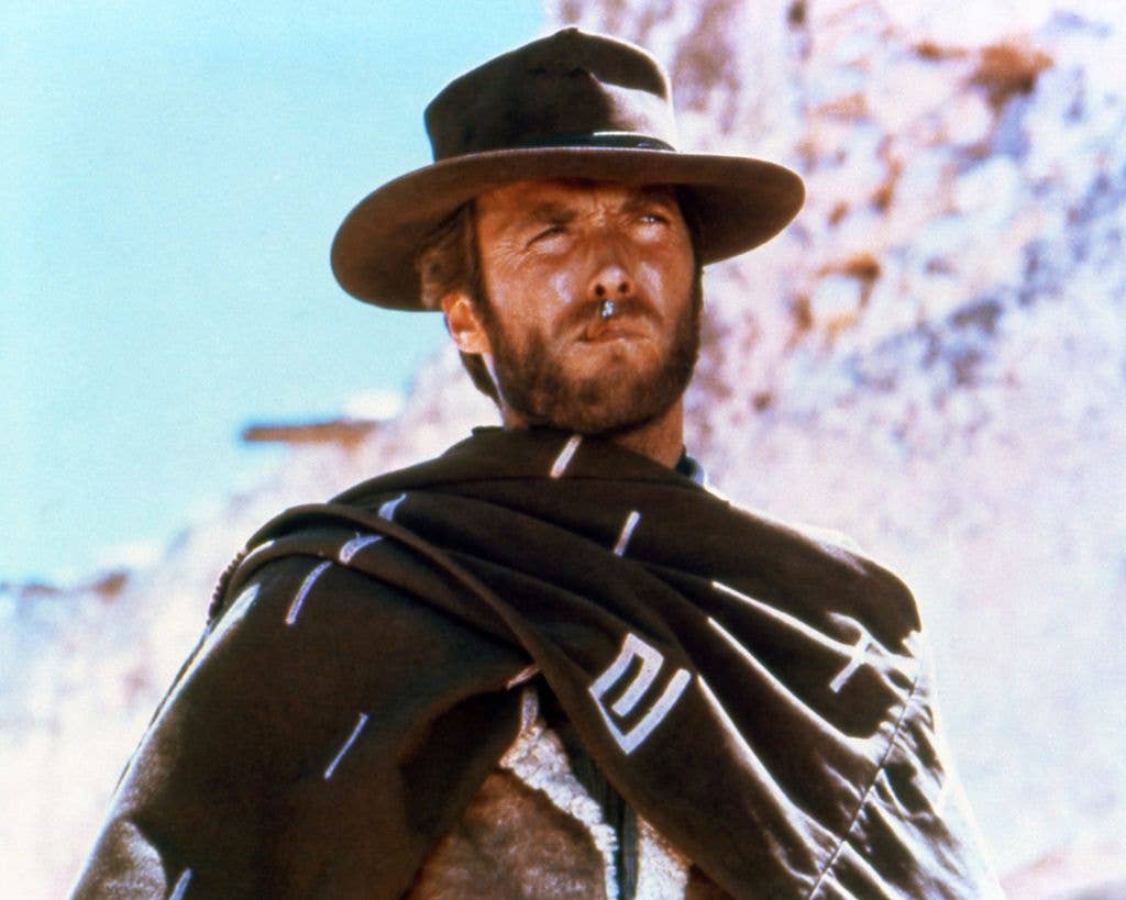 Clint Eastwood smoking a cigar, wearing a brown hat and poncho in a publicity portrait  for the film, A Fistful of Dollars