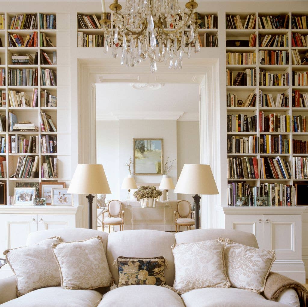 Elegant living room with bookshelves, chandelier, white couch, and framed artwork.