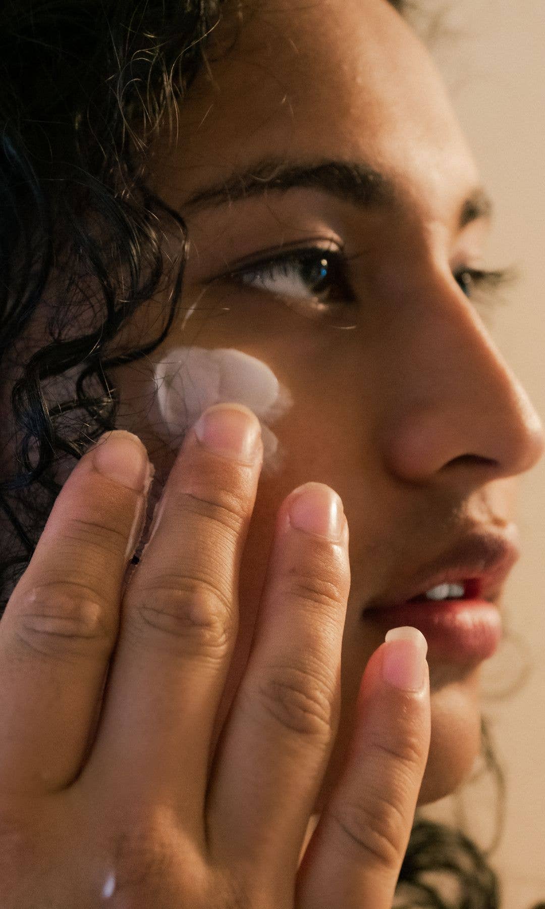 Model with brown skin putting cream on her face