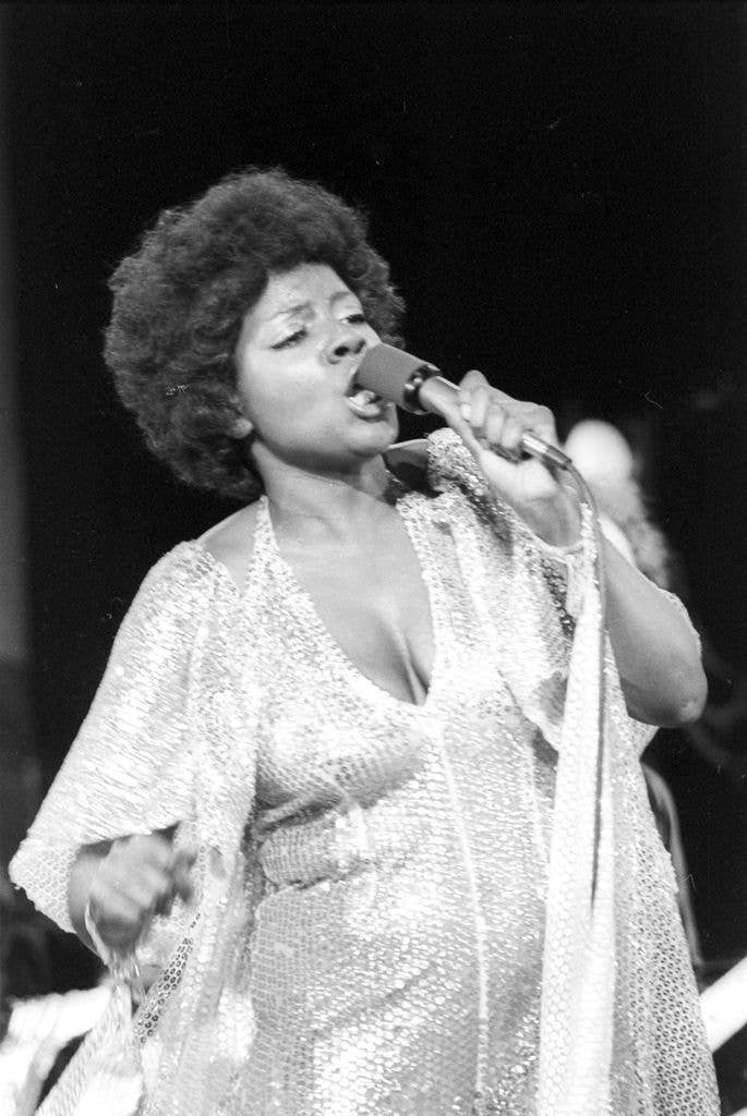 Gloria Gaynor on stage singing into a microphone.