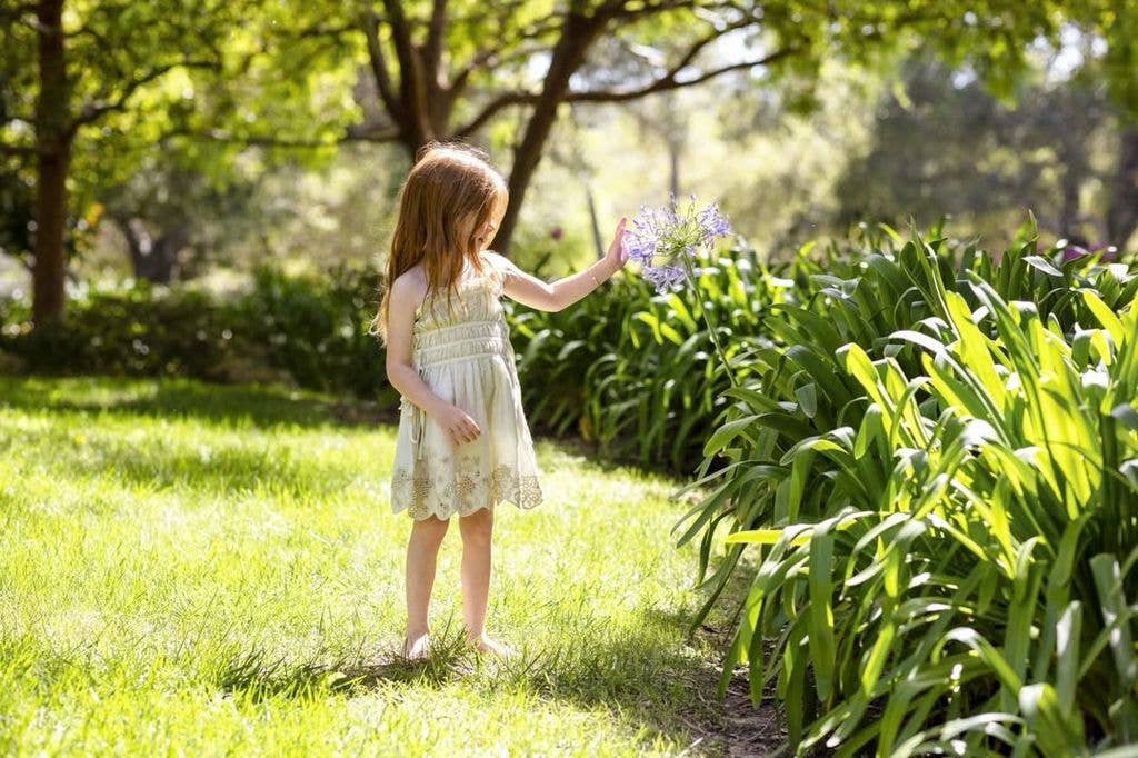 Princess Lilibet walking barefoot in the garden looking at flowers