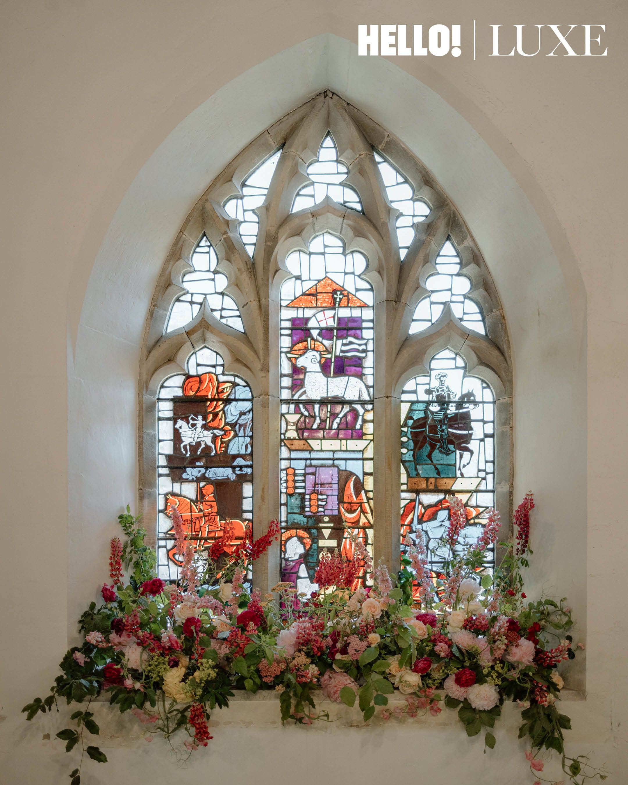 Locally sourced summer flowers fill the stone window sill of All Saints' Church beneath the traditional stained glass window