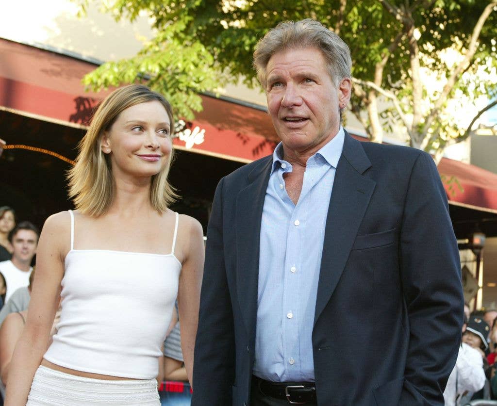 Calista Flockhart looking up at Harrison Ford while they pose for photographers in smart dress at a movie premiere