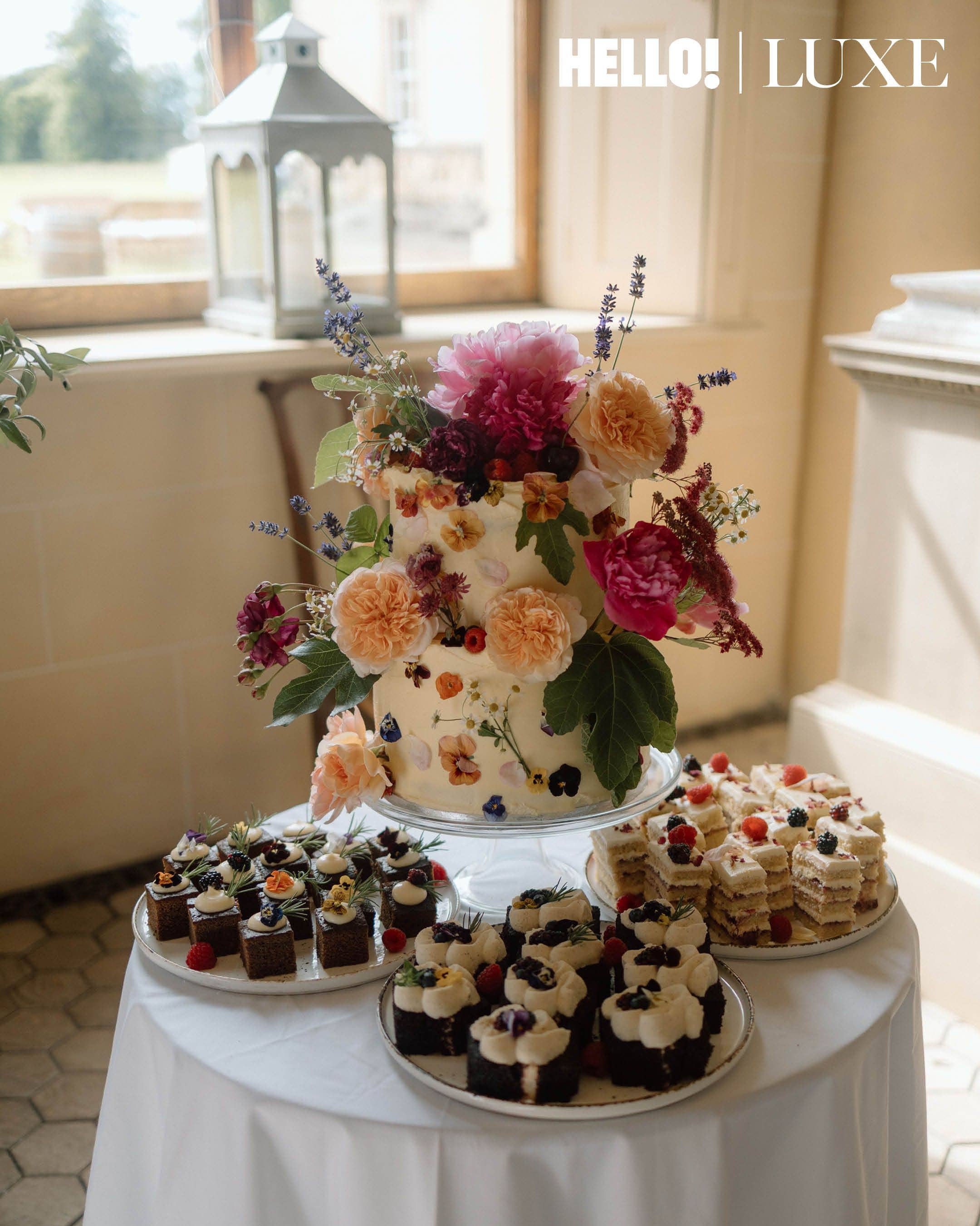 The beautifully arranged cake table features floral decorations that echo the midsummer theme, presented alongside a selection of artisanal sweet treats for the guests