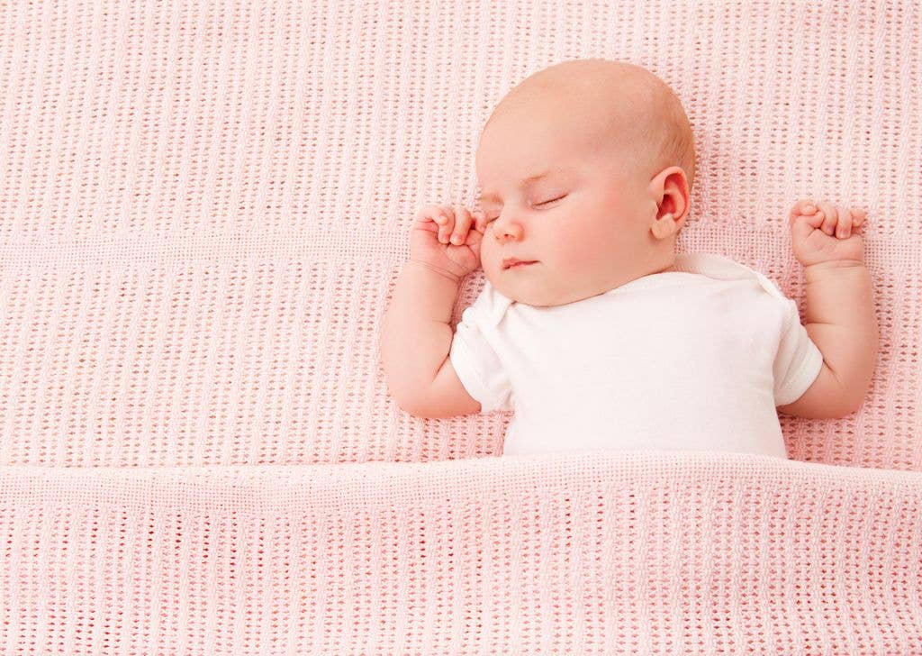 A sleeping baby girl covered with a pink blanket