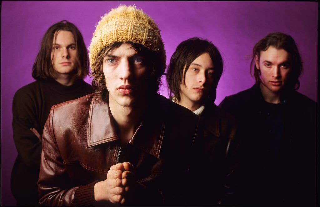 The Verve pose in front of a purple background.