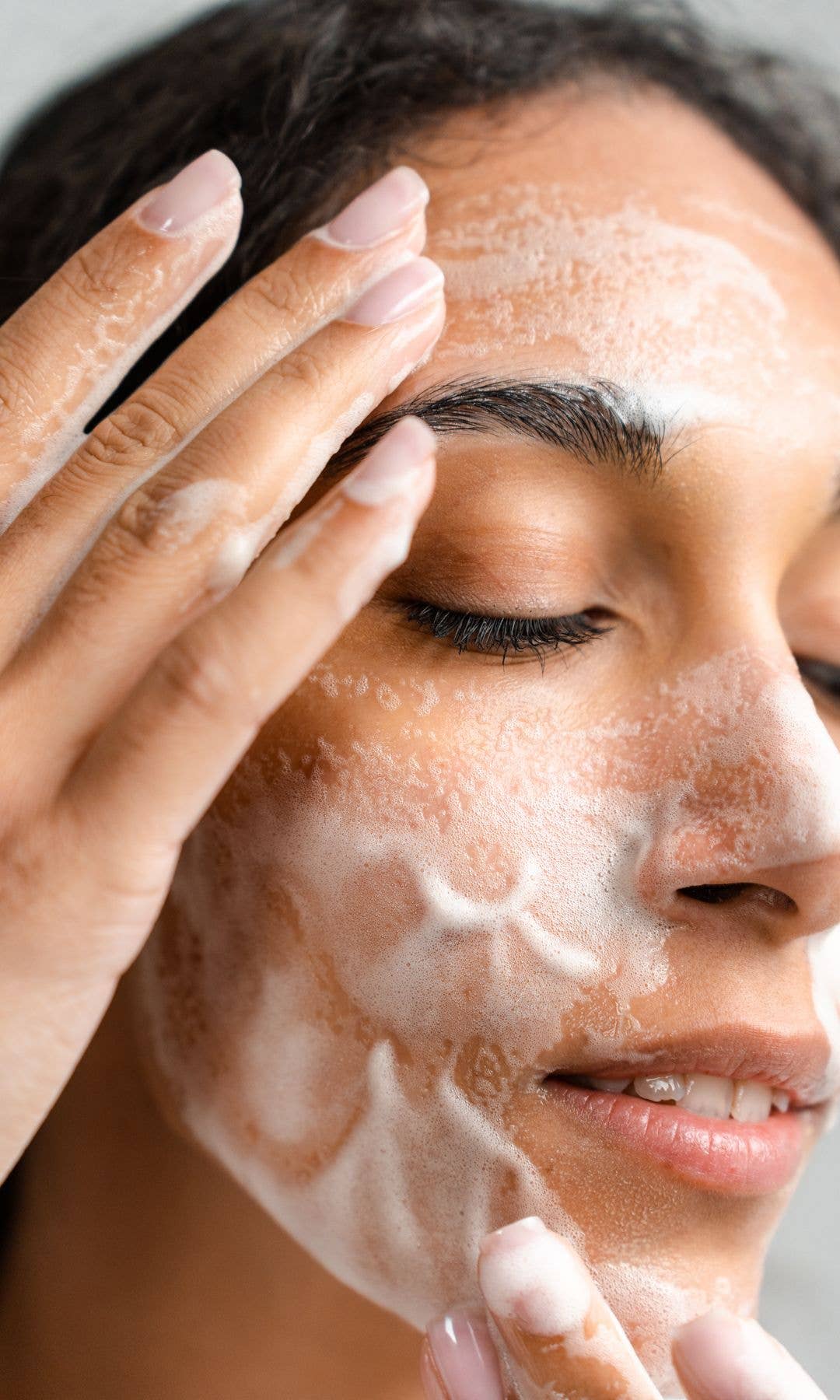 Model with a foaming cleanser on her face and her eyes closed 