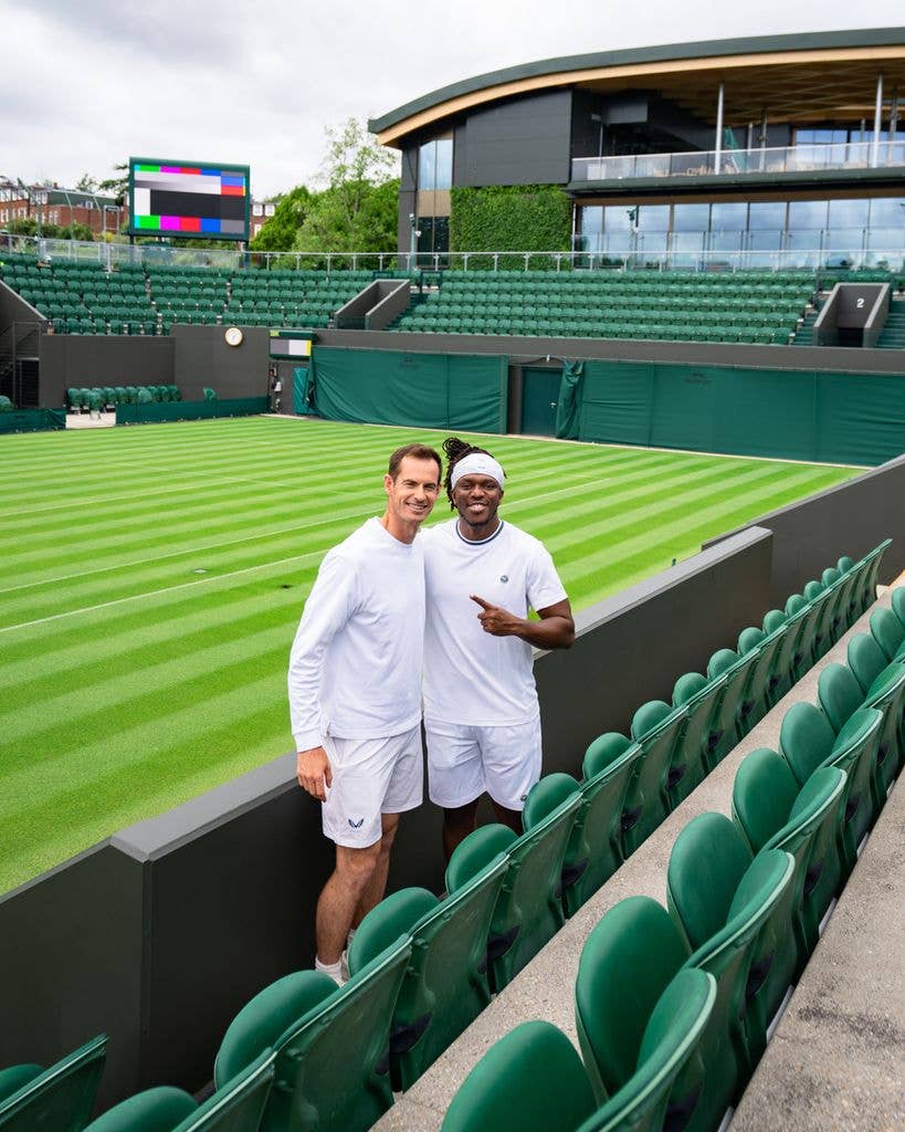 Andy Murray and KSI in white outfits standing on a tennis court, smiling.