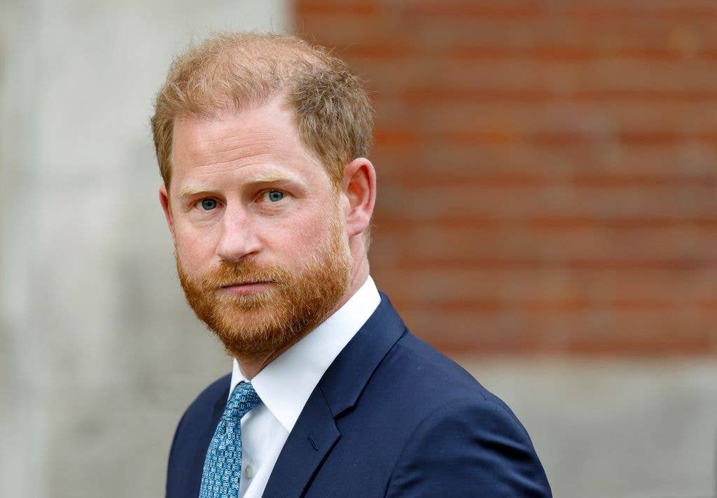 Price Harry in a navy suit and blue tie.