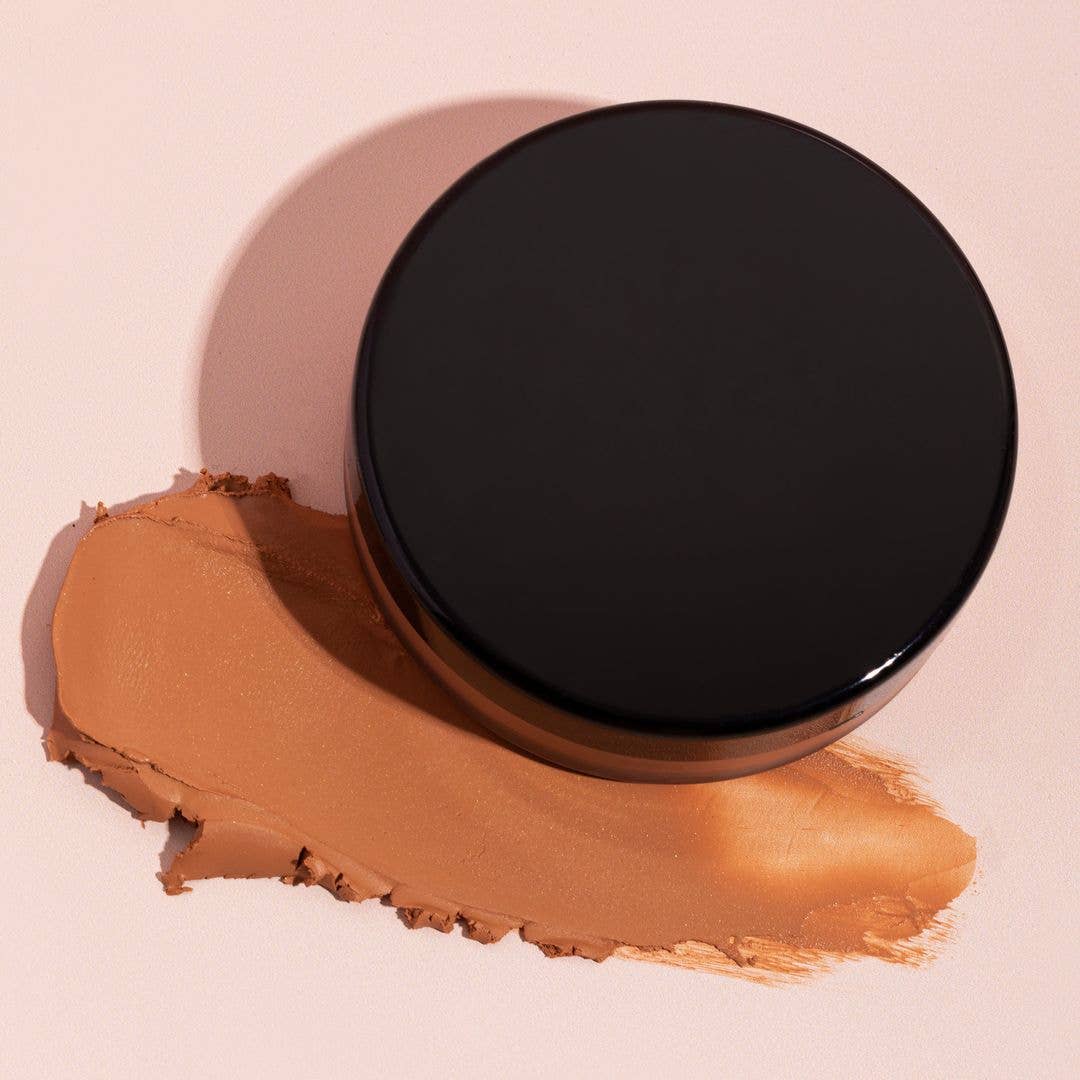A pot of cream bronzer with a swipe of product next to it