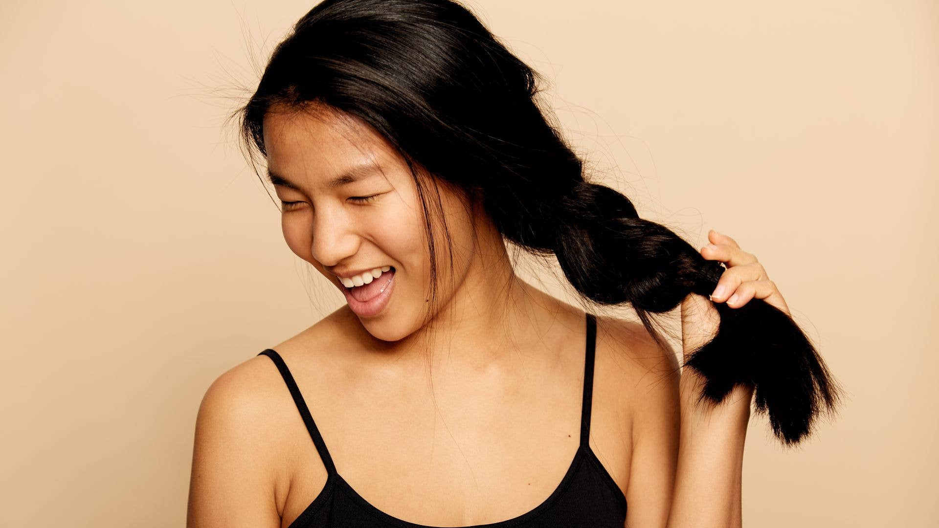 Asian woman with a thick plait pulling her hair 