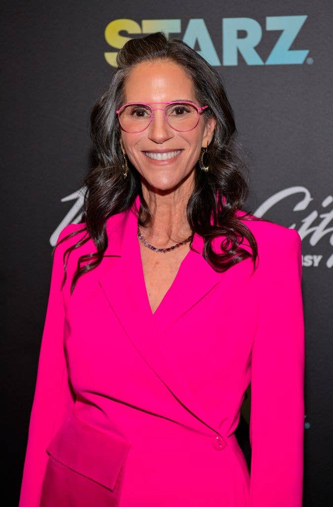 Jami Gertz in a bright pink trouser suit and bright pink glasses in 2025.