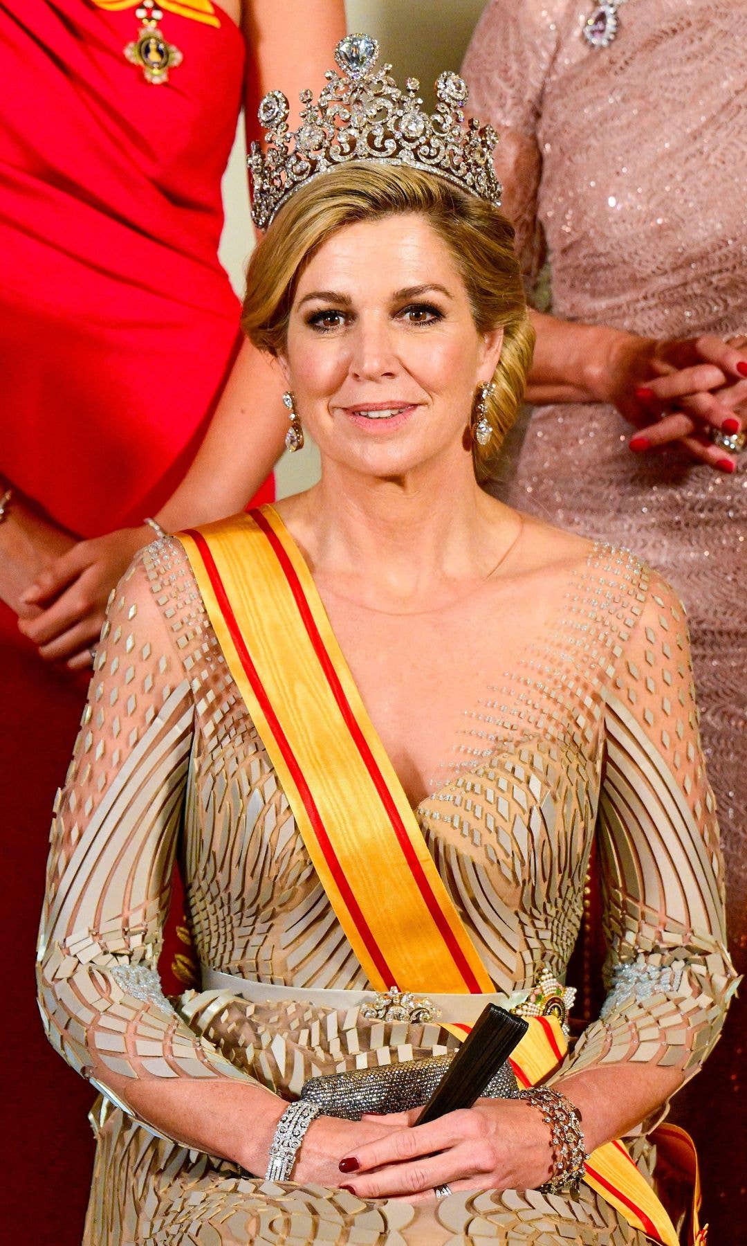 Queen Maxima sitting in a gold dress and crown