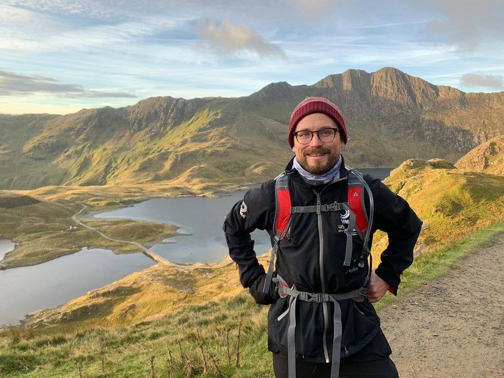 Man in hiking gear with a mountain and lake in the background