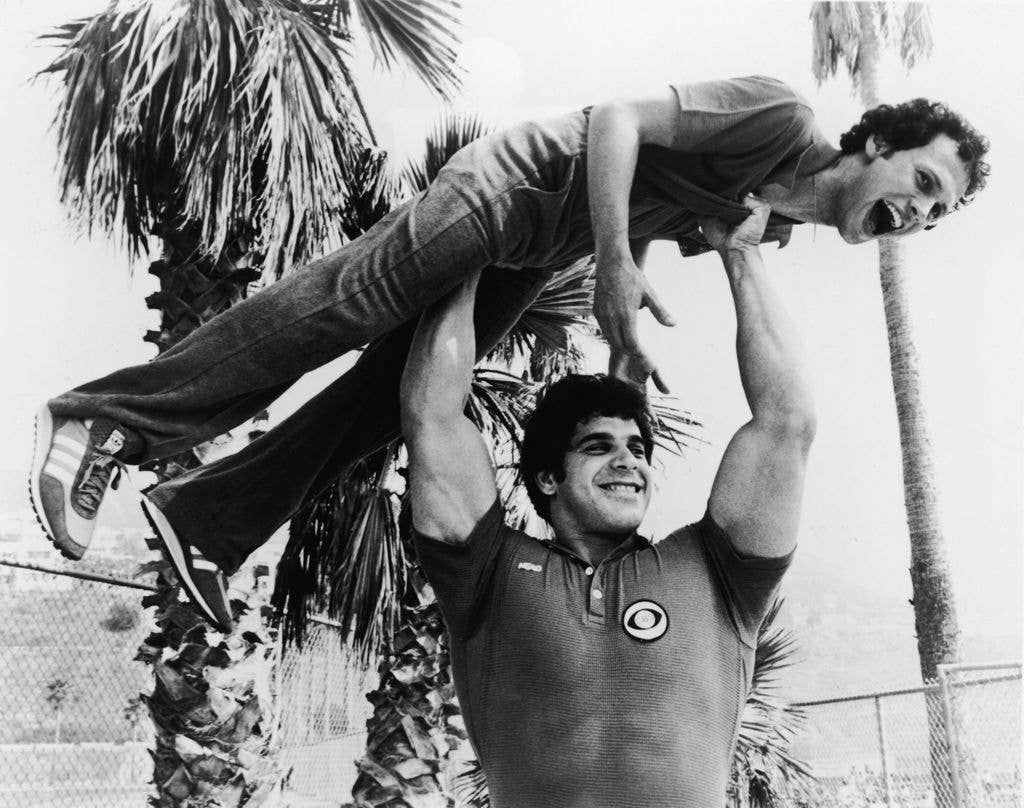 Lou holds actor and comedian Billy Crystal over his head on the set of 'Battle of the Network Stars'