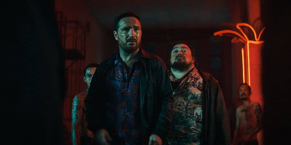 Frederick Lau and three other men stand in a dimly lit room with red lighting.
